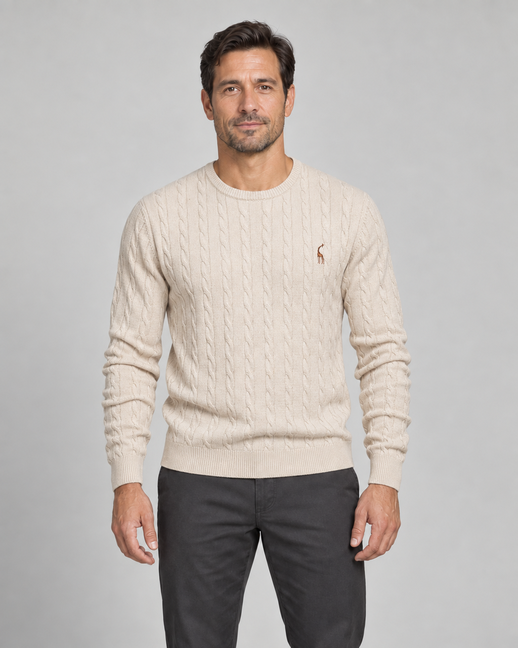 Front cropped view of a man wearing a light beige cable-knit crew-neck jumper with a small brown chest motif