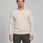 Front cropped view of a man wearing a light beige cable-knit crew-neck jumper with a small brown chest motif
