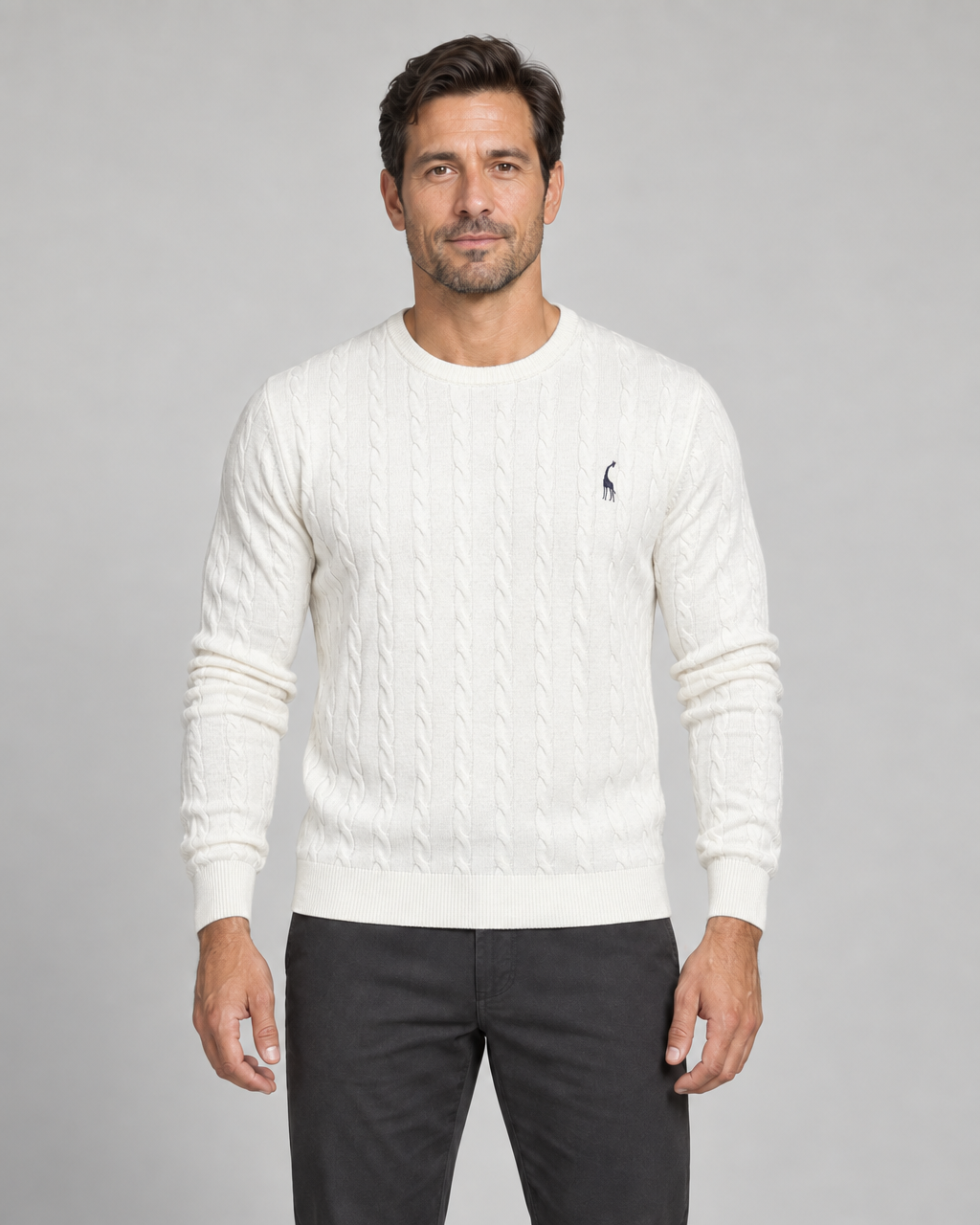 Front cropped view of a man wearing a white cable-knit crew-neck jumper with a small dark chest motif.