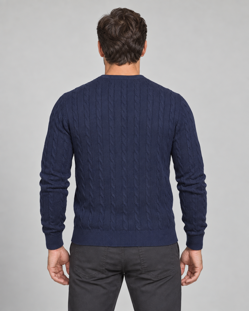 Rear cropped view of a man wearing a dark blue cable-knit crew-neck jumper.