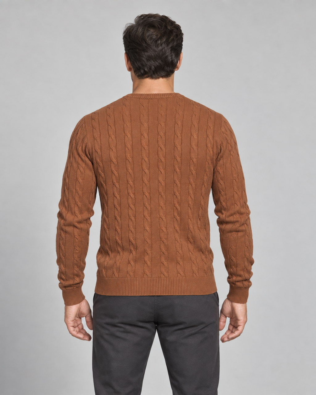 Man shown from behind wearing a brown cable-knit crew-neck jumper, cropped at the thighs.