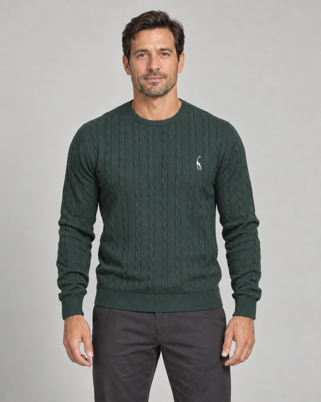 Front cropped view of a model wearing a dark green cable-knit crew-neck jumper with a small white chest motif