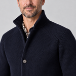 Close-up of a man wearing a navy textured jacket with a raised collar and button front.