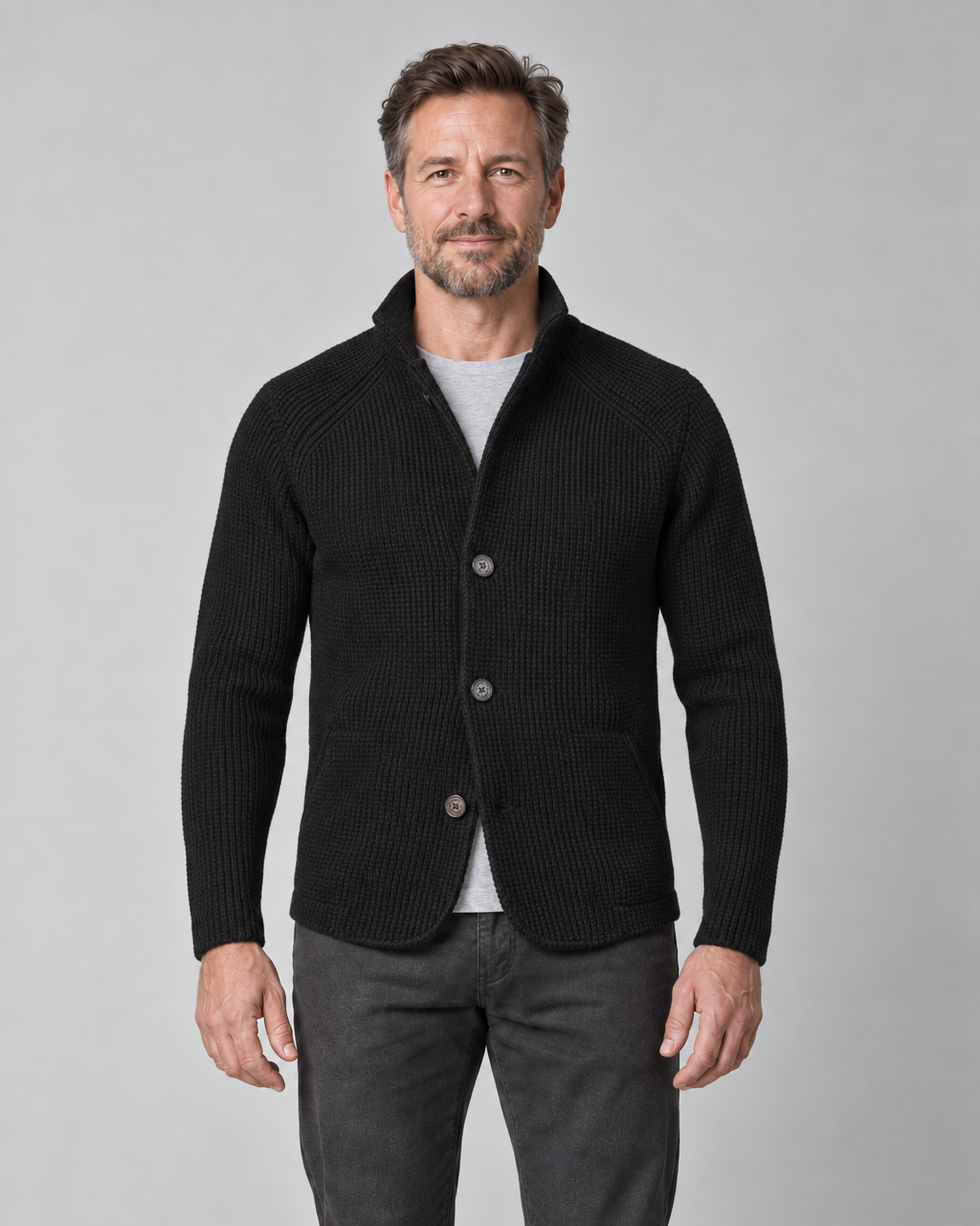 Front cropped view of a man wearing a black textured jacket with a raised collar, three buttons and patch pockets