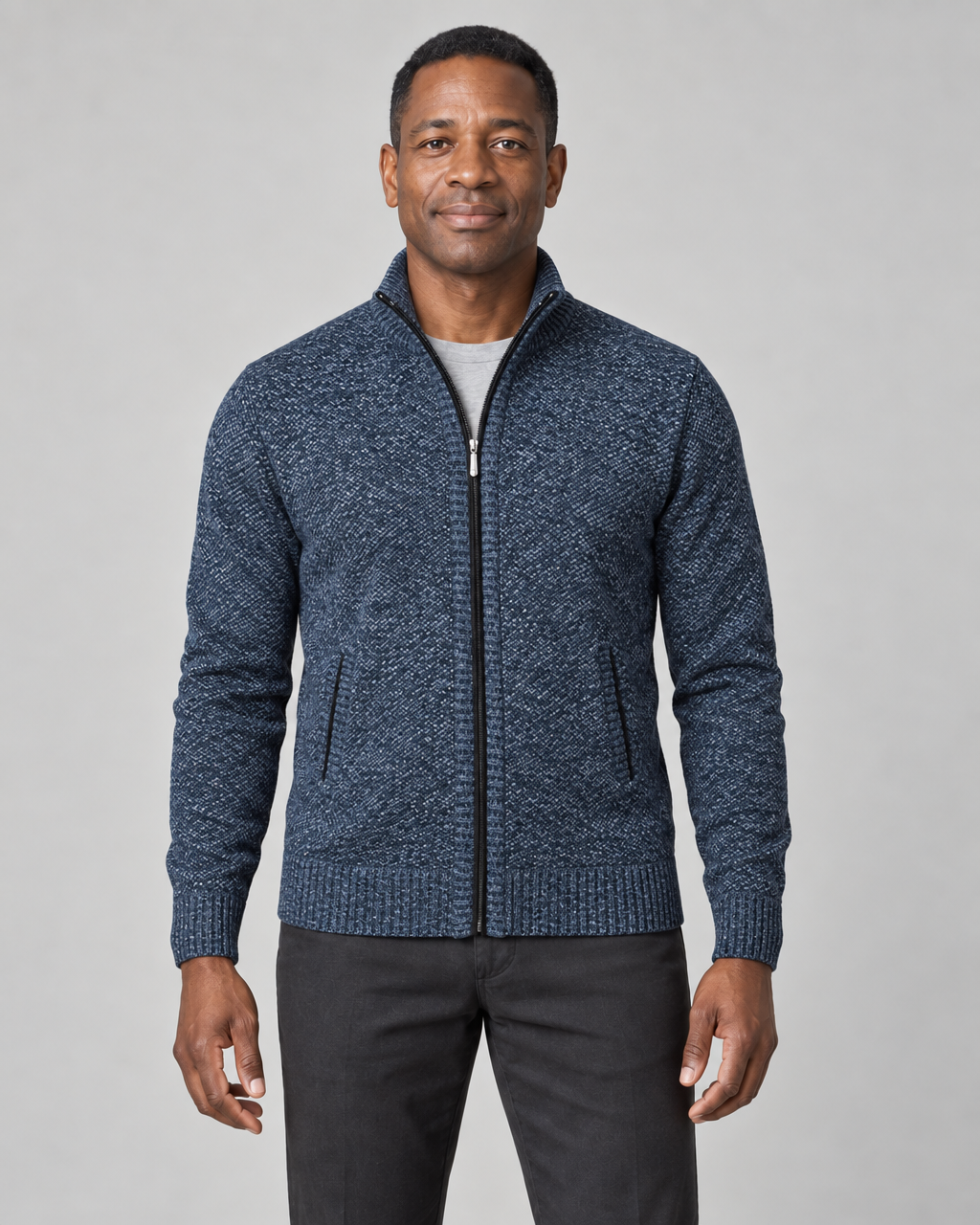 Front view of a model wearing a blue marled zip-up sweater with a stand collar and two side pockets