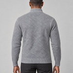 Back view of a light grey textured sweater with a ribbed high neck, cuffs and hem, worn with black trousers.