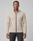 Front cropped view of a men's light khaki zip-up sweater with a stand collar and black zip and pocket trims.
