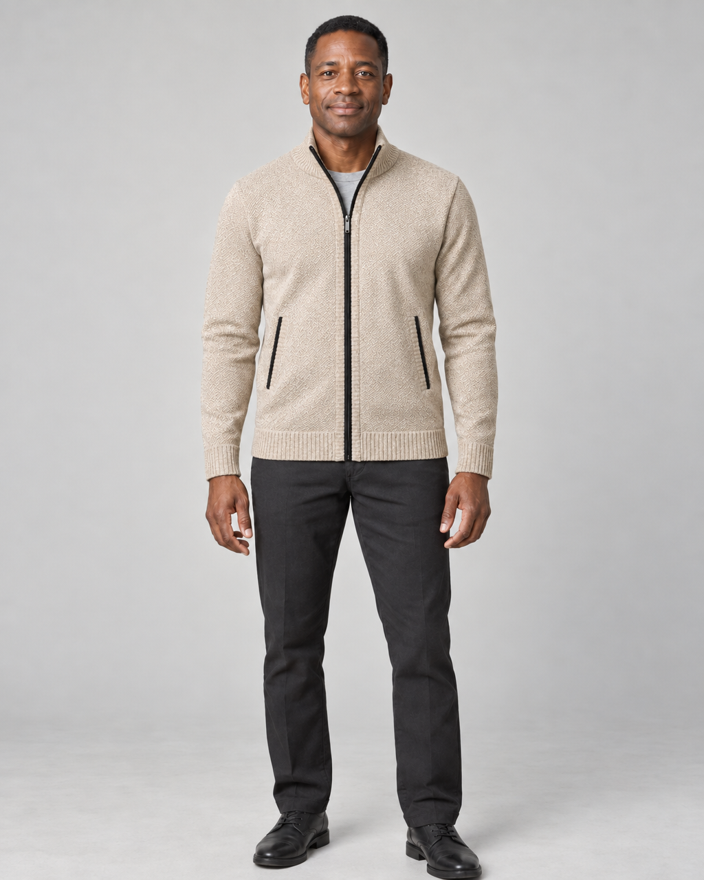 Man wearing a light khaki zip-up sweater with a stand collar and black trim, full-length front view