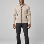 Man wearing a light khaki zip-up sweater with a stand collar and black trim, full-length front view