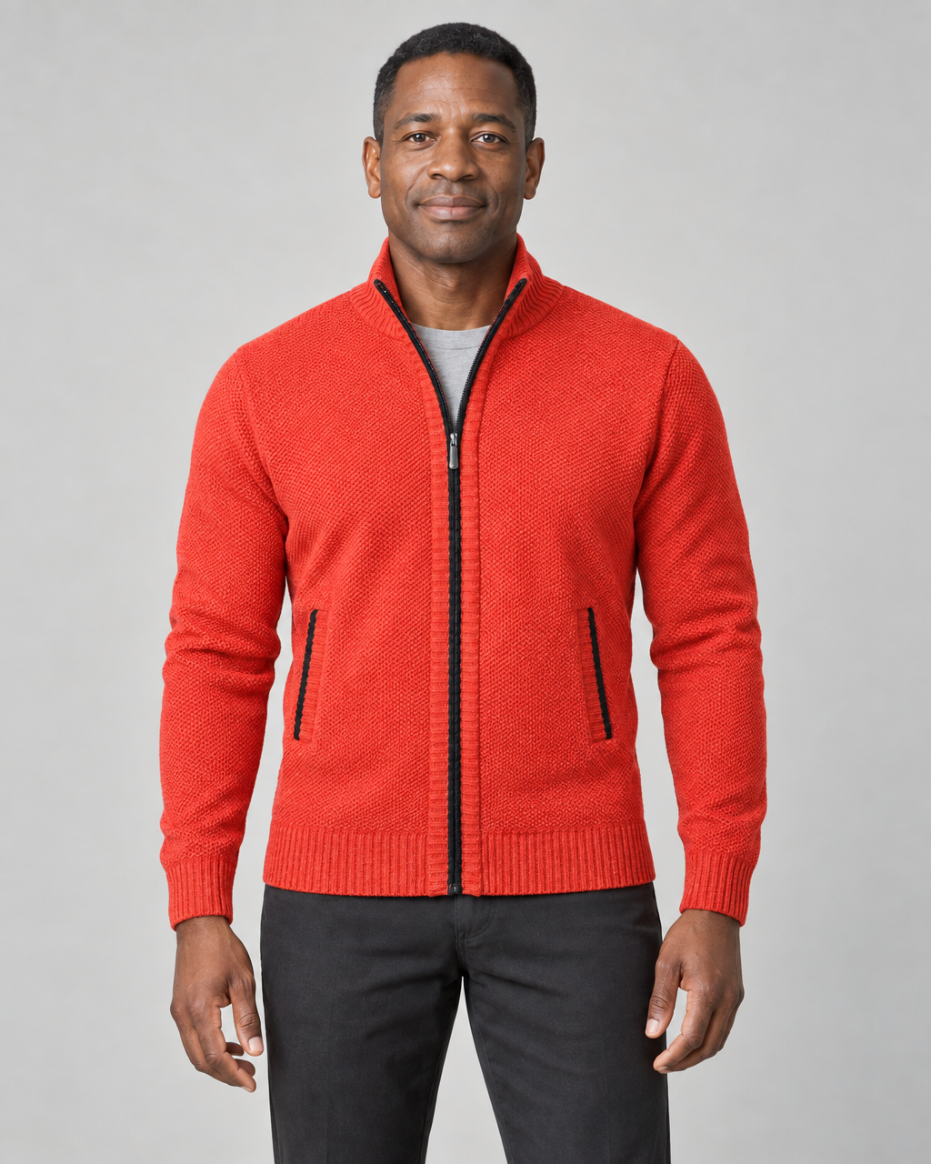 Cropped front view of a man wearing an orange zip-up sweater with a stand collar and black-trimmed pockets.