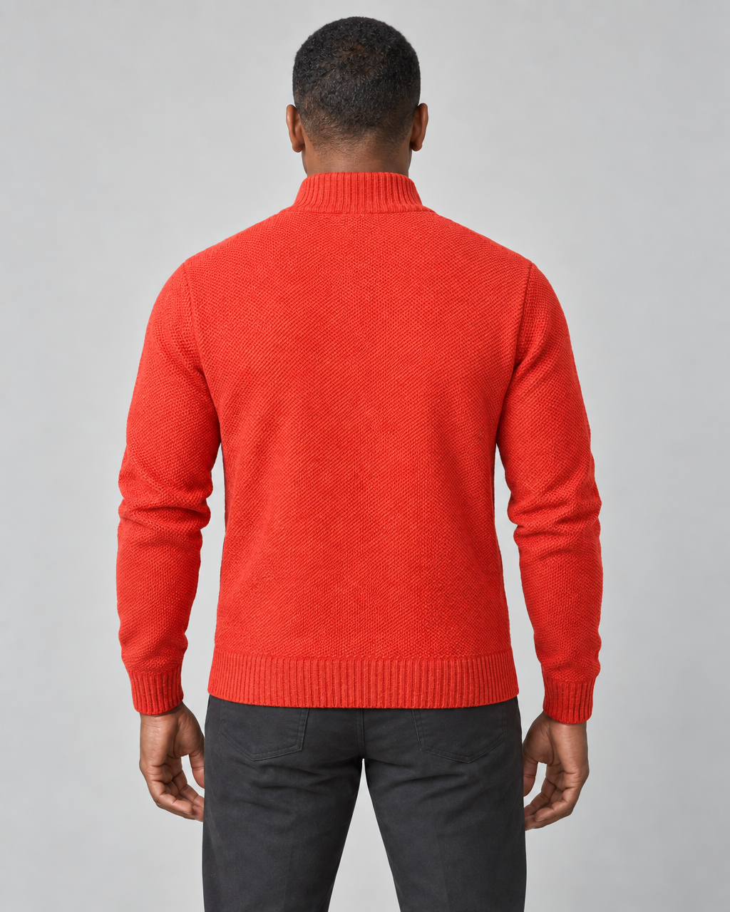 Rear view of a man wearing a bright orange knitted roll-neck jumper, cropped from head to thighs