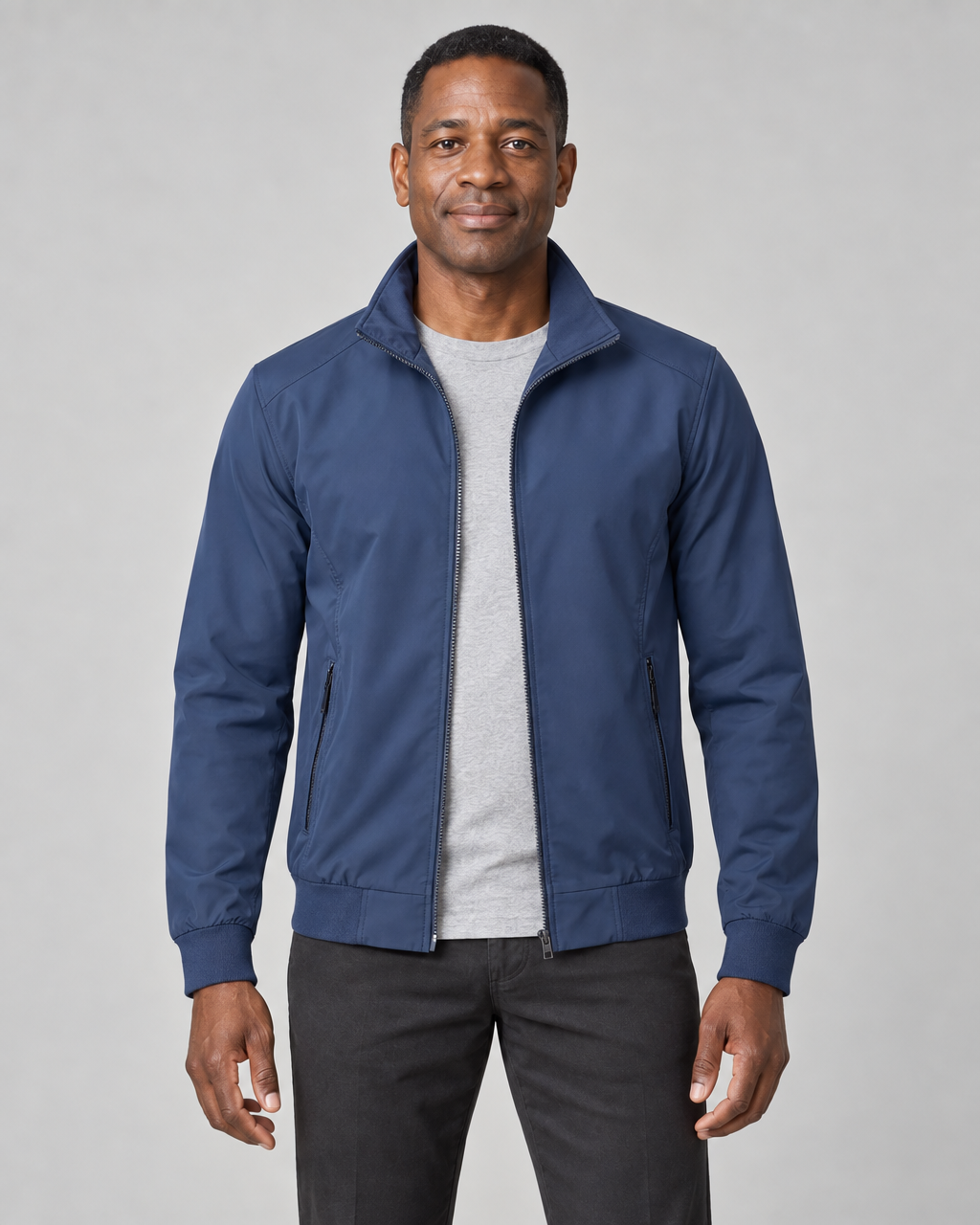 Front cropped view of a man wearing an open blue zip-up jacket with raised collar and zipped side pockets