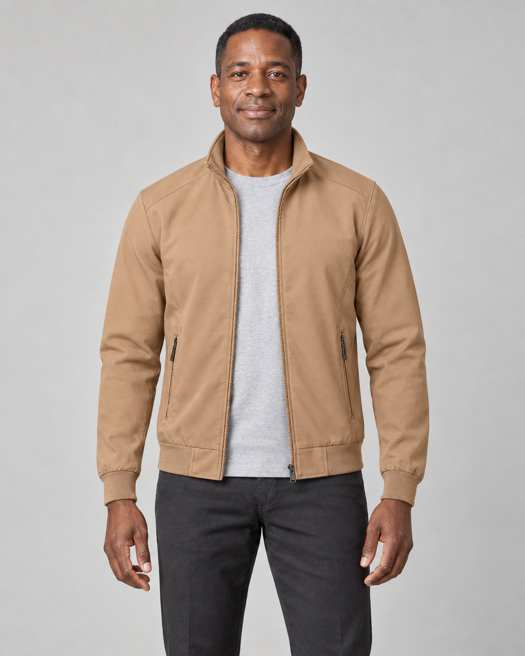 Front cropped view of a man wearing an open khaki jacket with a stand collar, ribbed cuffs and two zipped pockets.