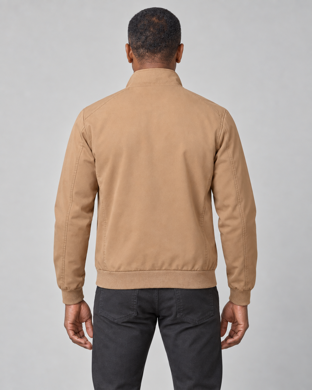 Back view of a man wearing a khaki jacket with a raised collar and ribbed cuffs and hem