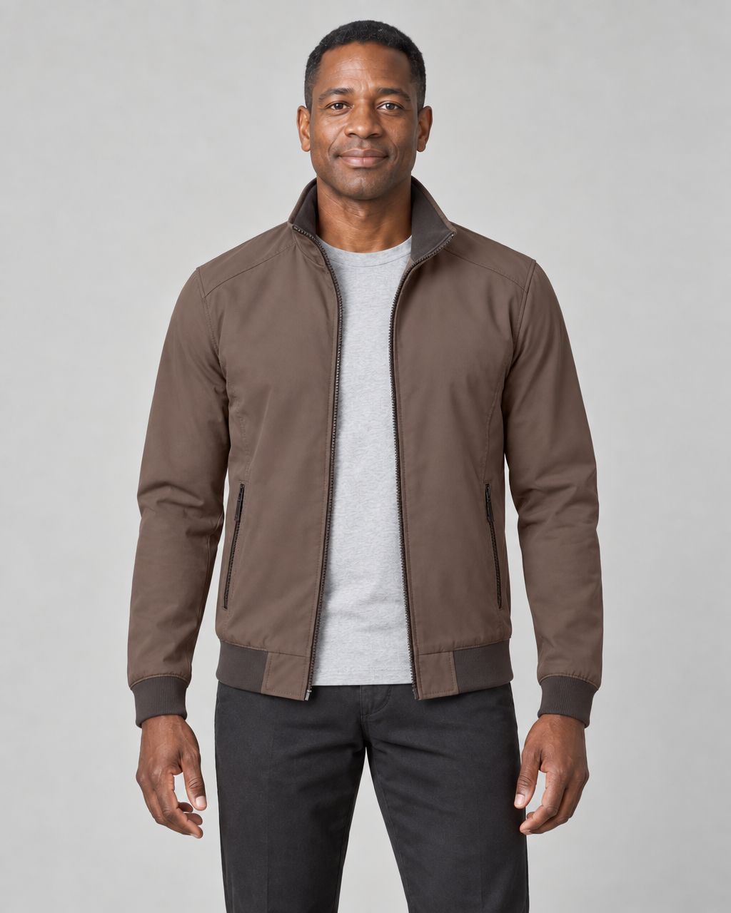 Front cropped view of a man wearing an open brown zip-up jacket with a raised collar and zipped side pockets