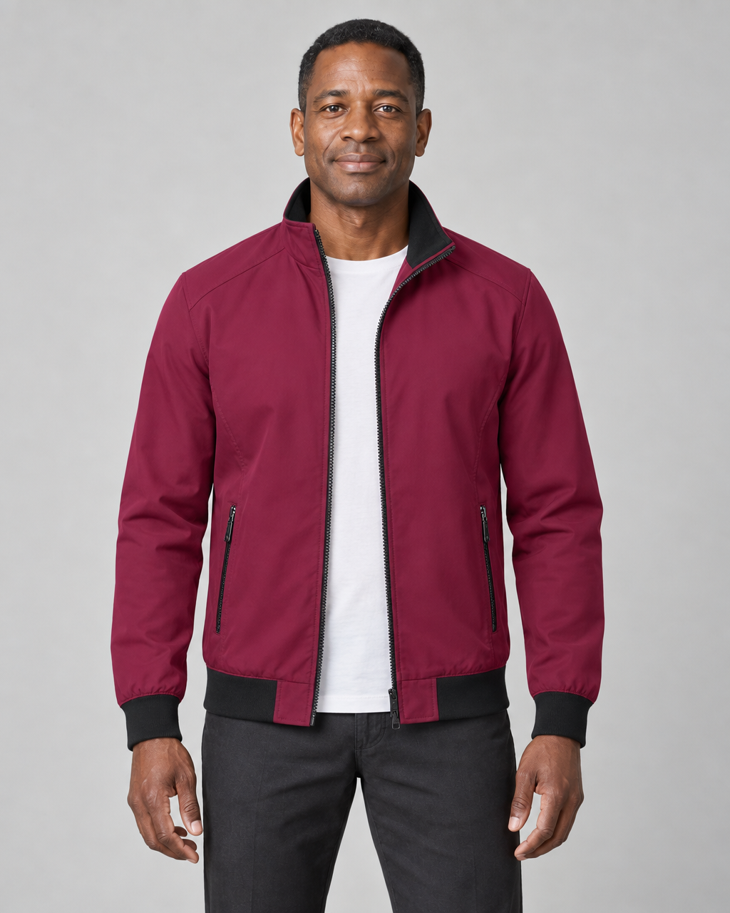 Front cropped view of a man wearing an open dark red jacket with black collar, cuffs, hem and zipped side pockets.