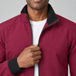 Close-up front view of a burgundy red jacket with a black-lined stand collar, black cuffs and zip fastening