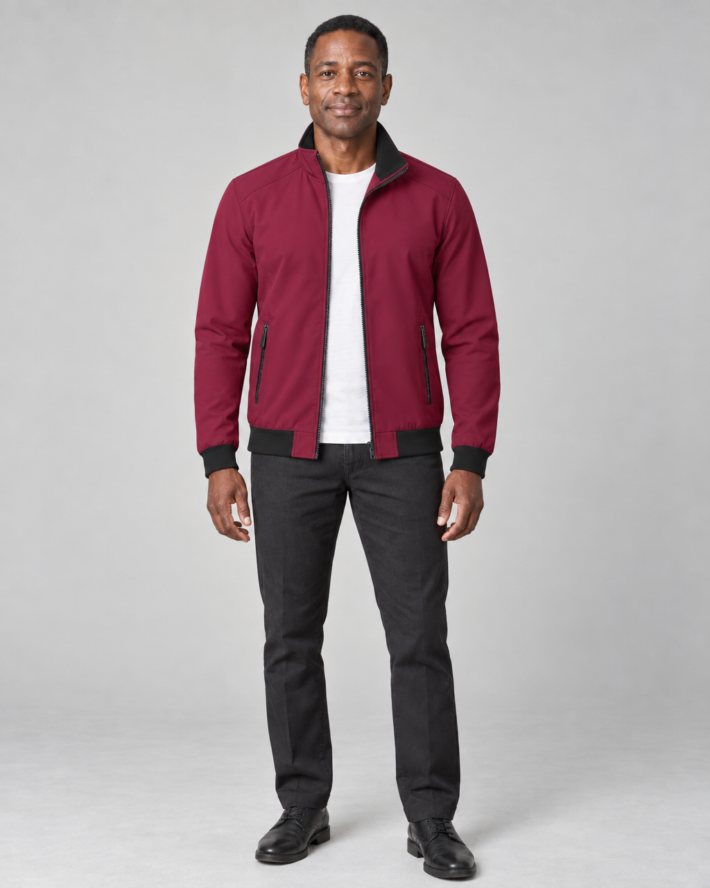 Full-body front view of a man wearing a burgundy zip-up jacket with black collar, cuffs and hem