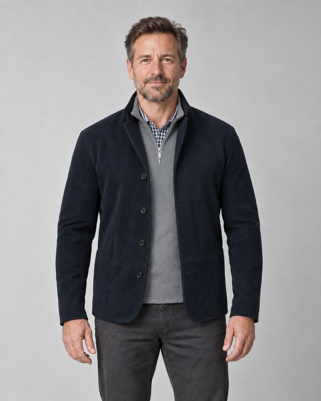 Front cropped view of a man wearing an open navy blazer with four buttons and two patch pockets.