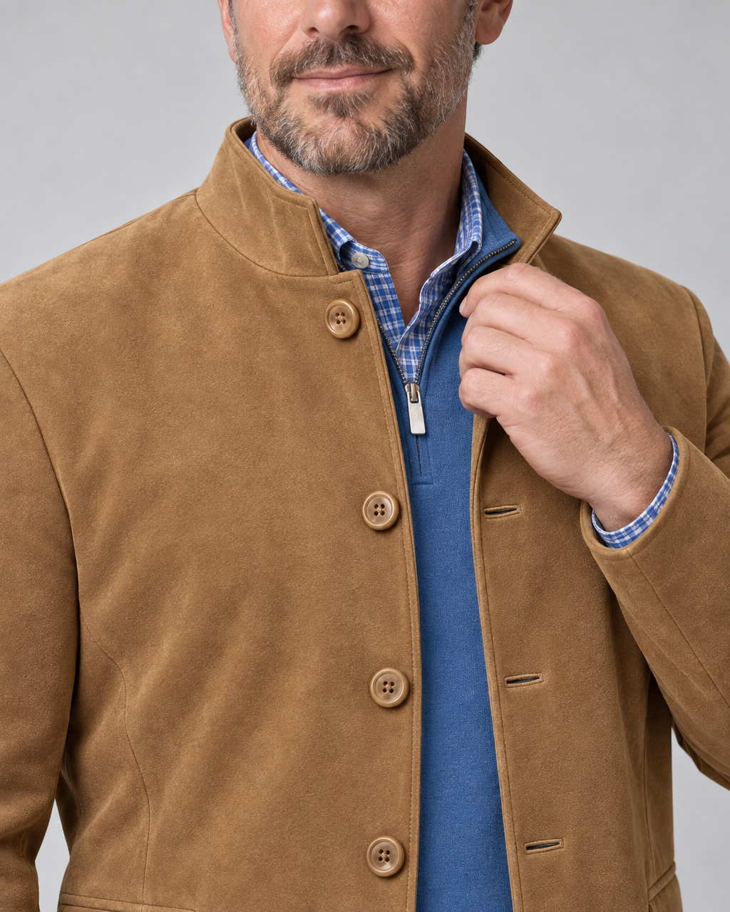 Close-up front view of a man wearing a brown button-front blazer with a stand collar over blue layers