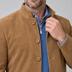 Close-up front view of a man wearing a brown button-front blazer with a stand collar over blue layers