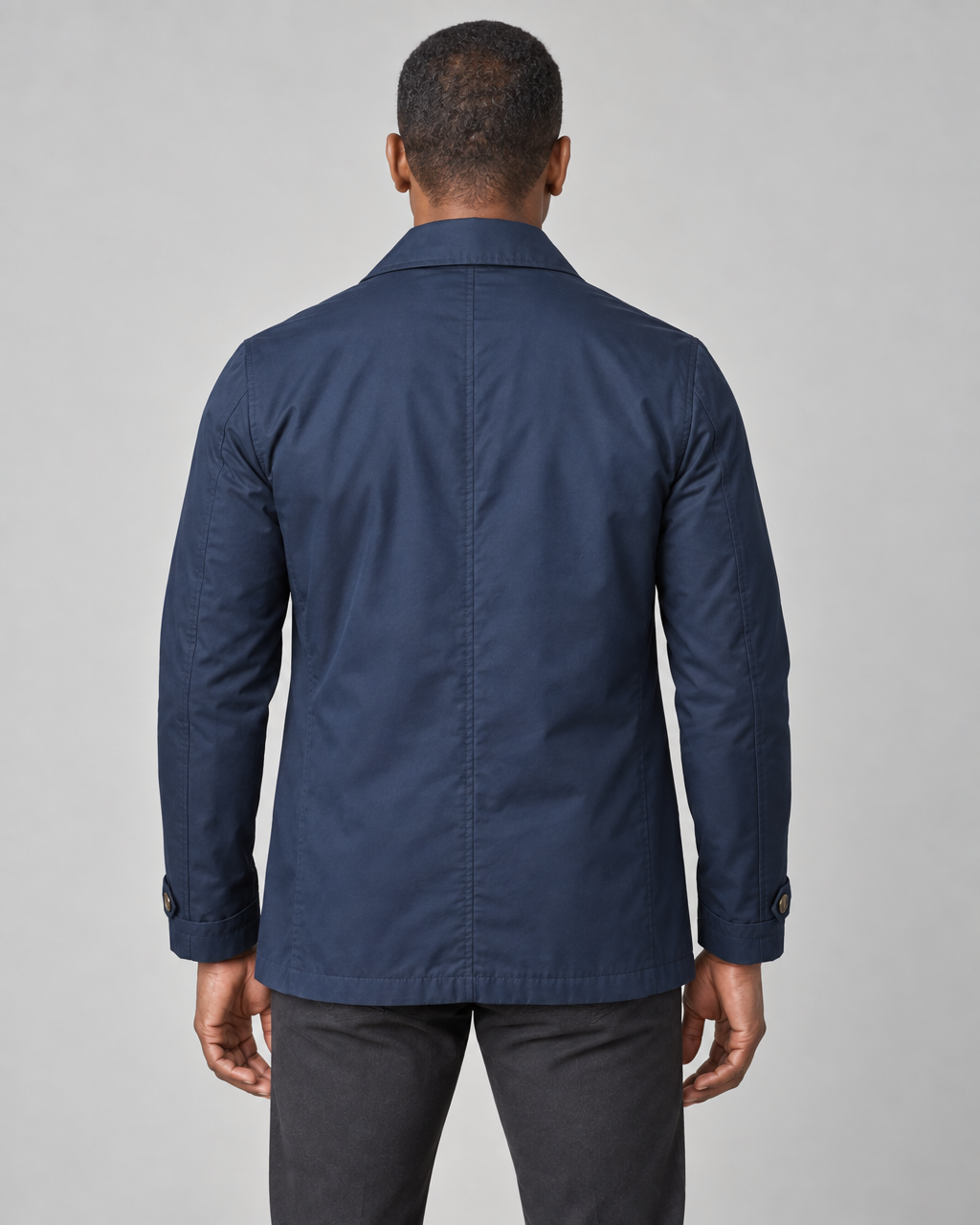 Back-view concept of a model wearing a navy blue short coat with a pointed collar and cuff tabs.