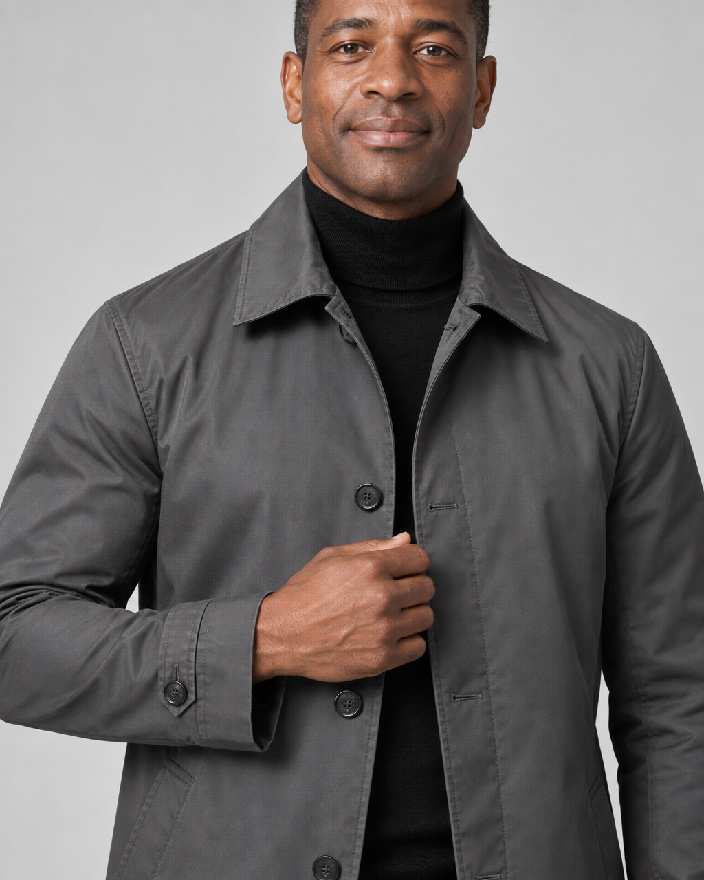 Close-up front view of a man wearing a grey coat with a pointed collar, dark buttons and buttoned cuff tabs