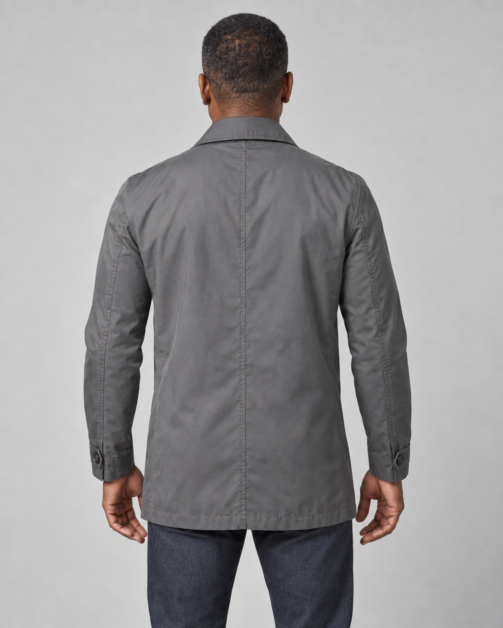 Back view of a model wearing a grey mid-length coat with a pointed collar and buttoned cuffs.
