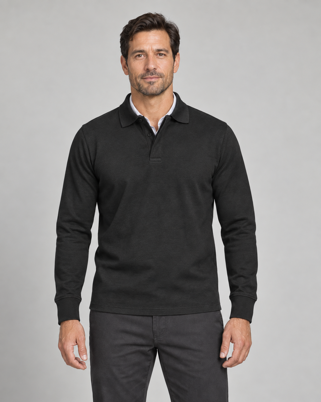 Front cropped view of a man wearing a black long-sleeved polo shirt with a button placket and fitted cuffs.